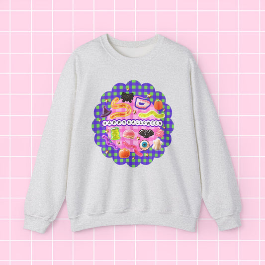 A light heather gray crewneck sweatshirt featuring a colorful retro graphic with the text 'HAPPY BIRTHDAY' on a pink and purple plaid scalloped background, displayed against a pink grid backdrop.
