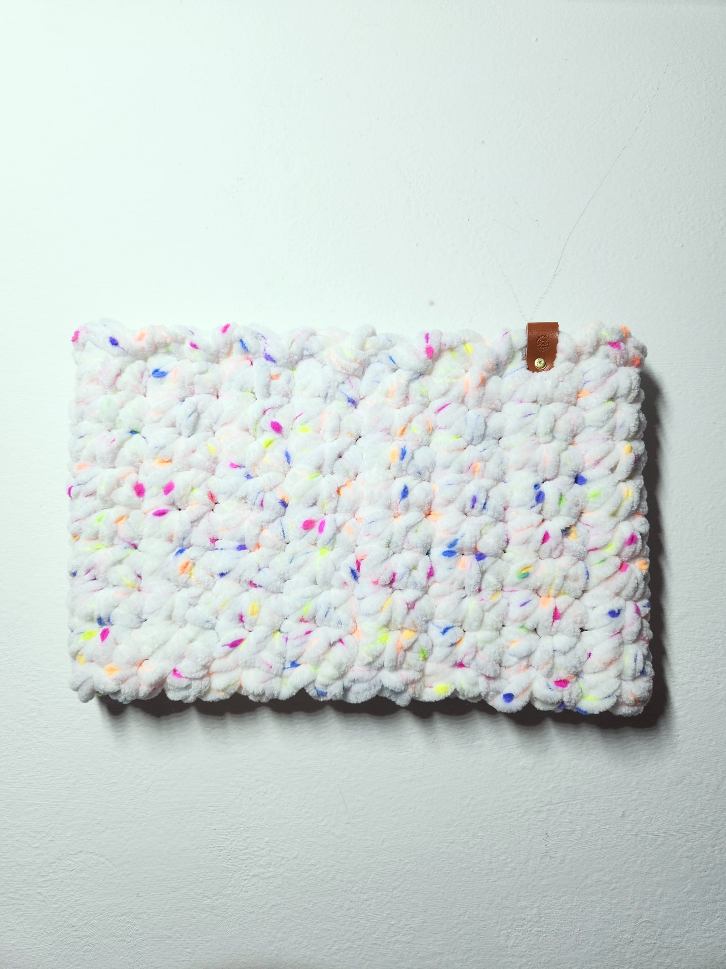 Textured white clutch with colorful speckles on a light gray background
