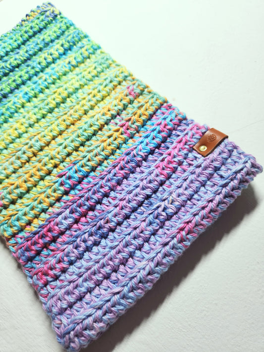 Multicolored crocheted hat with a brown leather patch on a light gray background