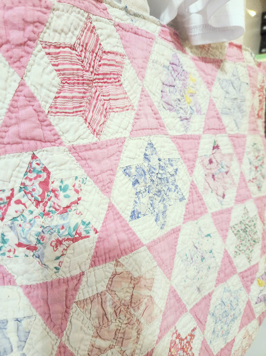 Quilt with pink and white hexagonal pattern, featuring floral designs.