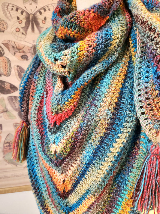 Multicolored crocheted shawl with tassels on a patterned background
