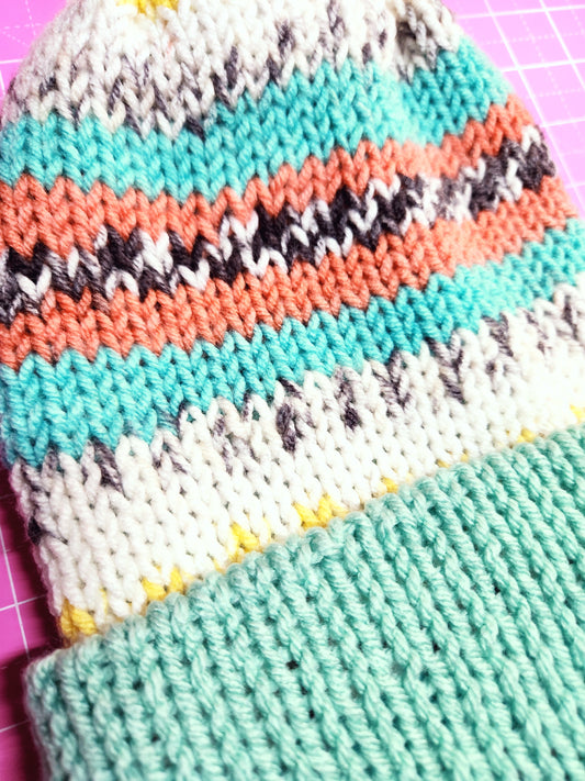 Close-up of knitted fabric with colorful zigzag pattern on a pink surface