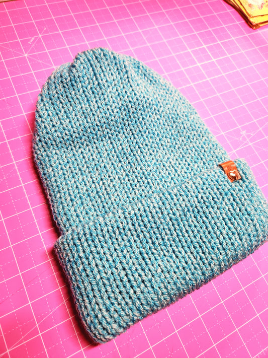 Teal knitted pouch on a pink grid background