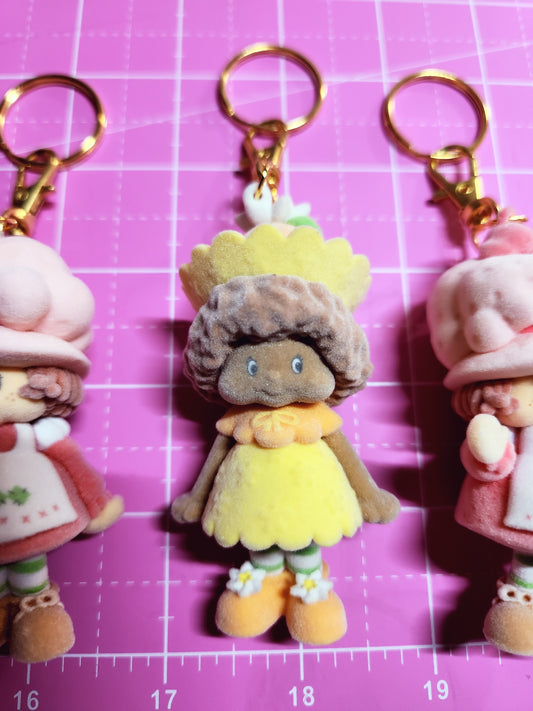 Keychains shaped like cartoon characters on a pink grid background