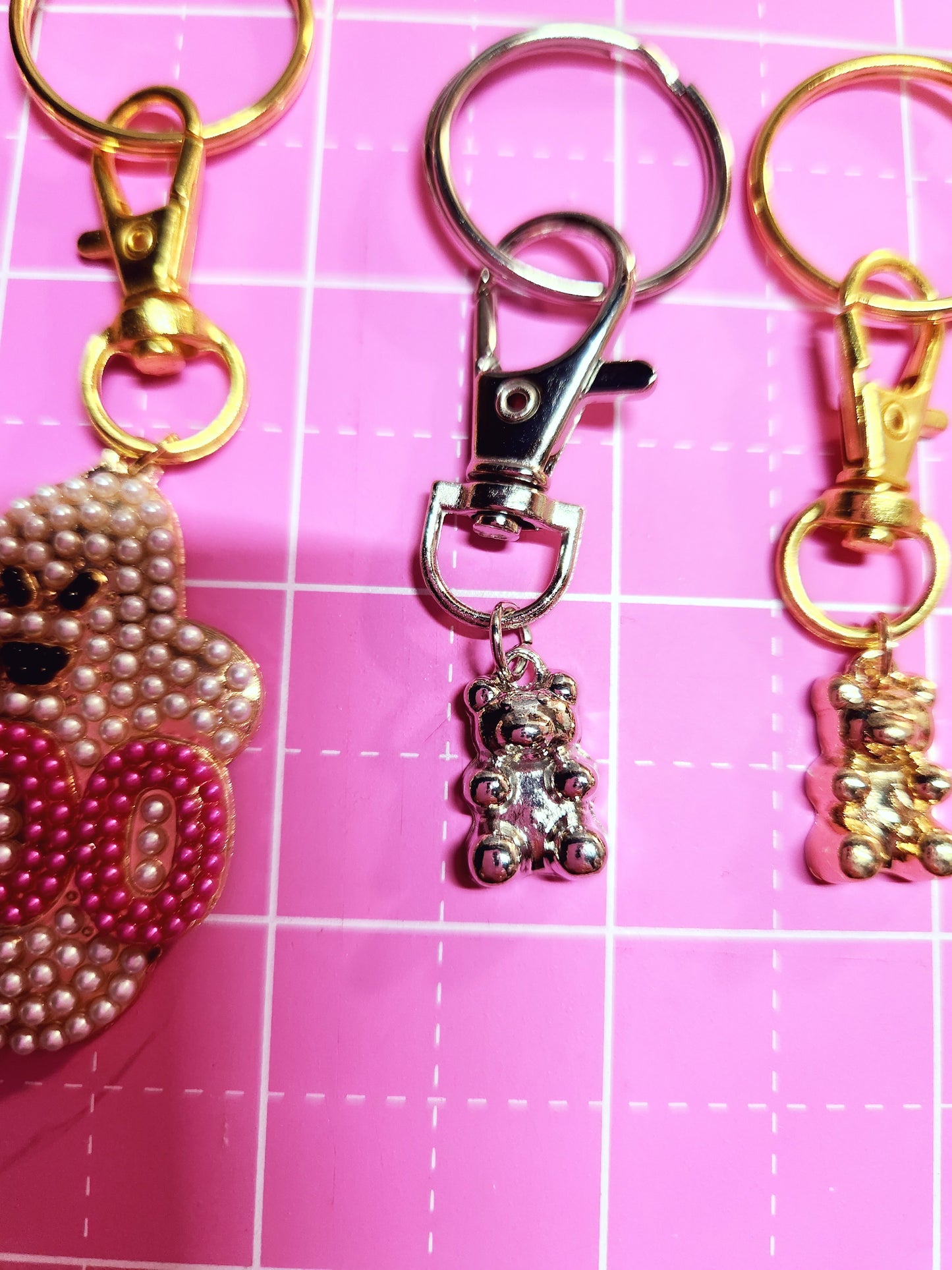 Keychains with decorative elements on a pink grid background