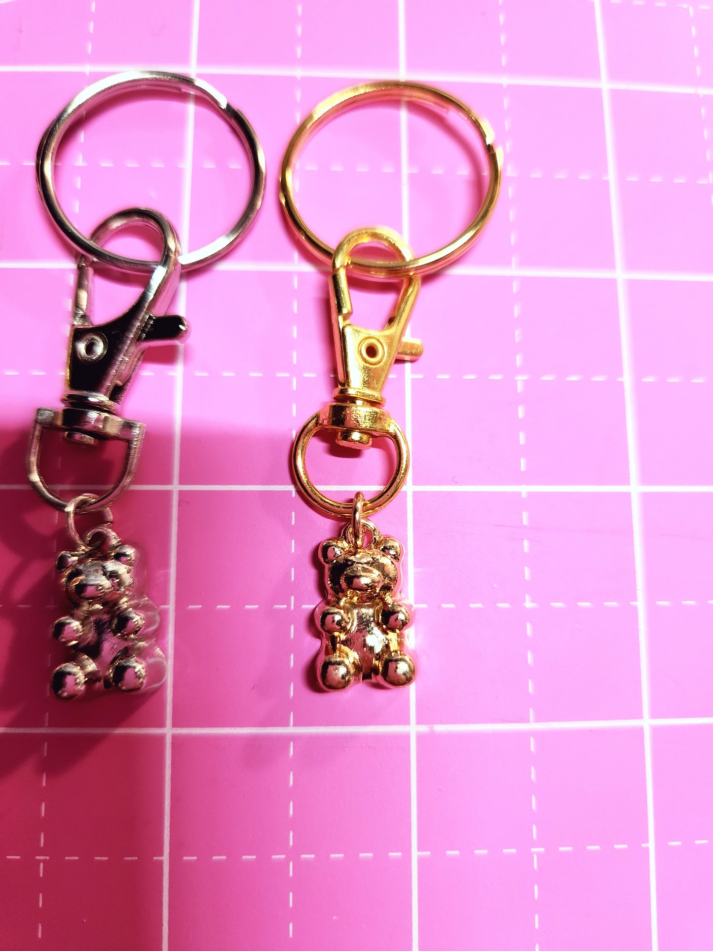 Gold and silver keychains on a pink grid background