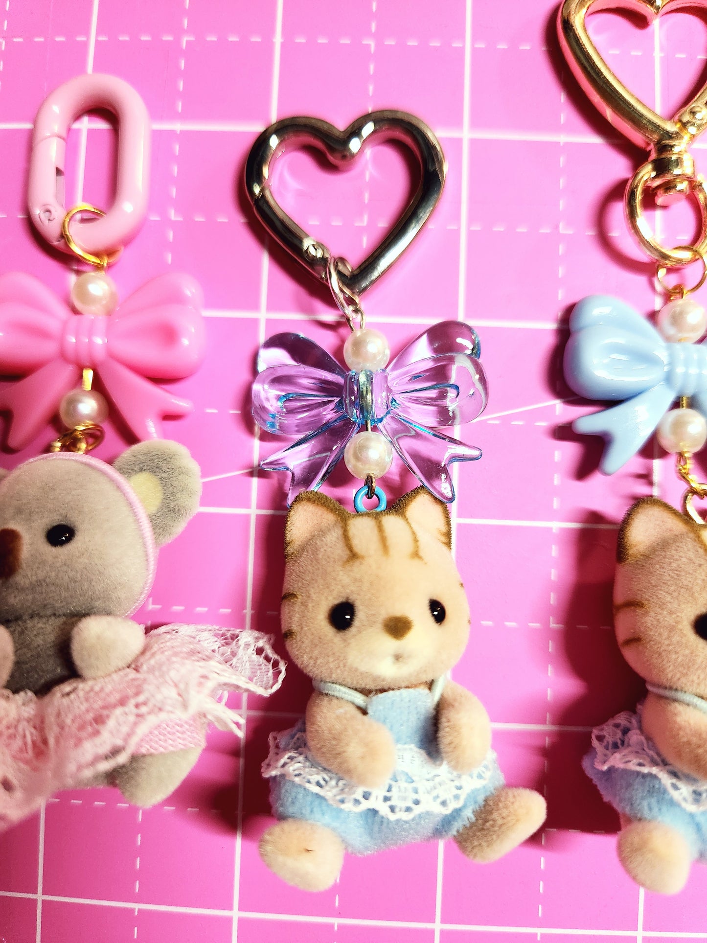 Collection of decorative keychains and charms on a pink grid background