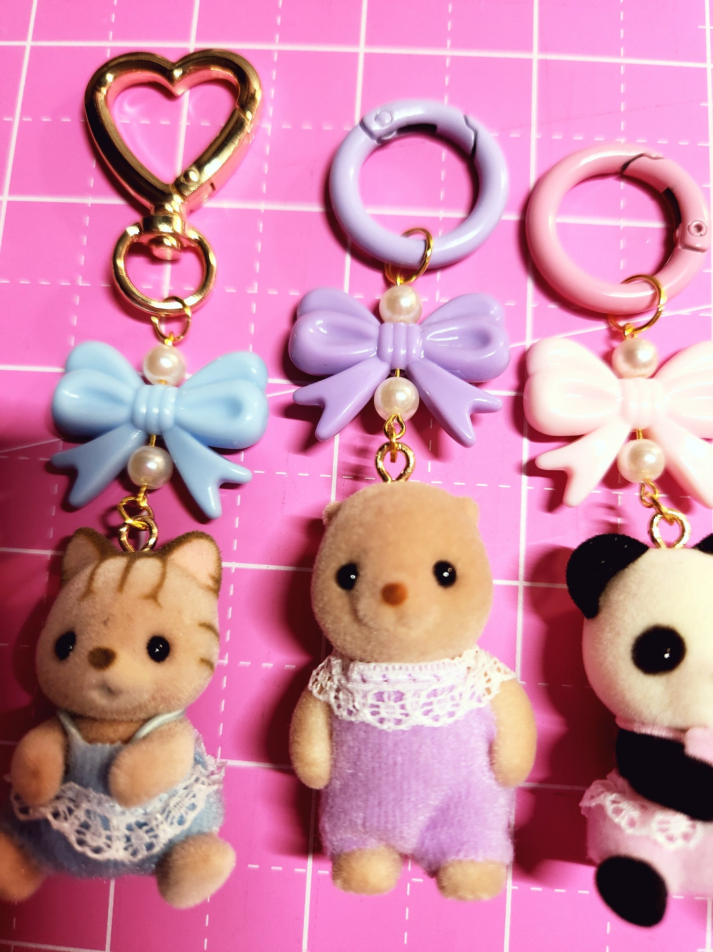 Collection of small plush toys and keychains on a pink grid background