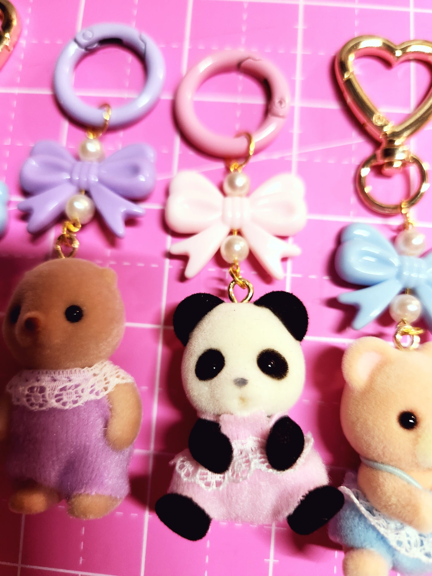 Collection of colorful keychains and charms on a pink grid background