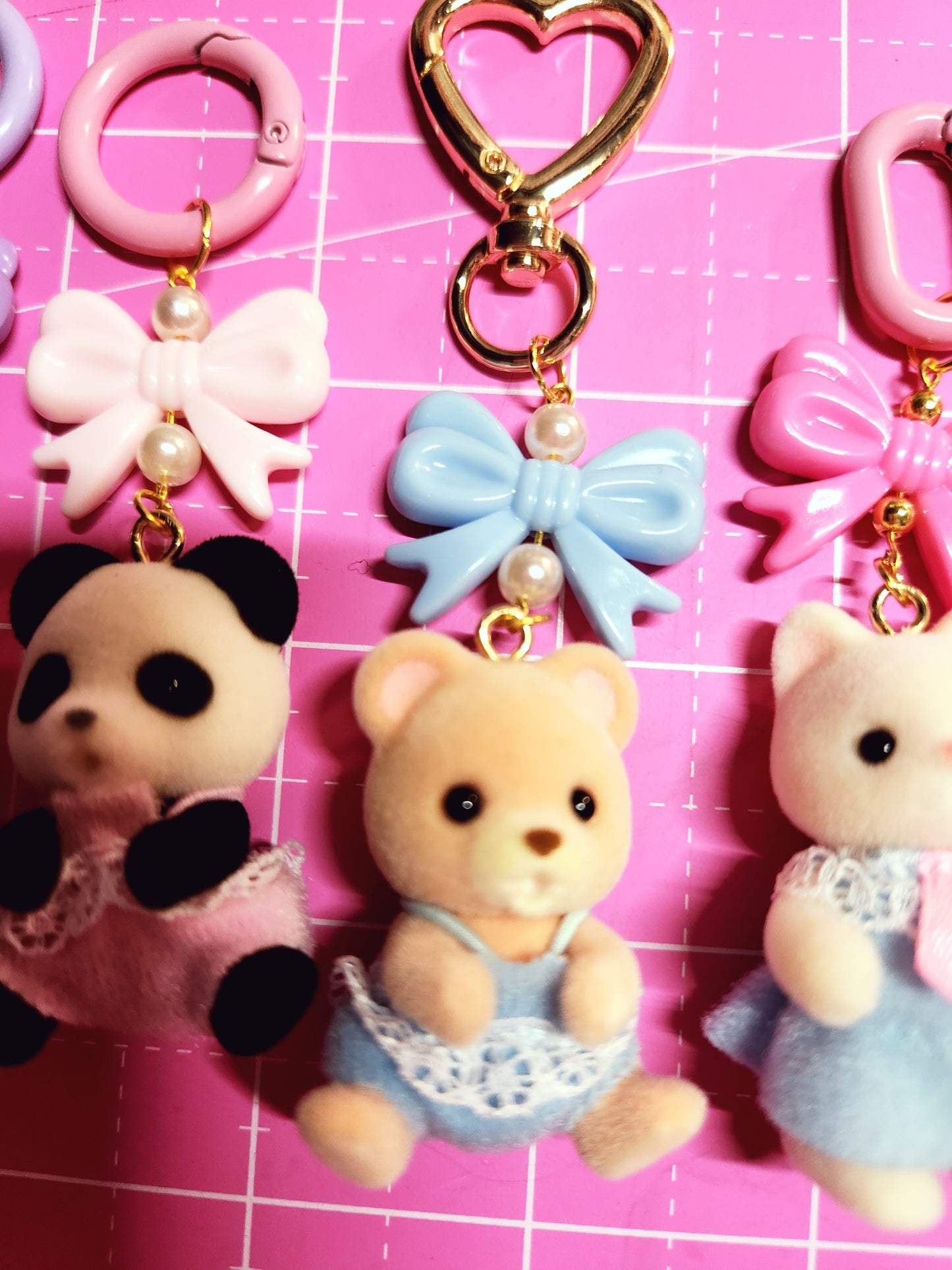 Collection of colorful keychains and charms on a pink grid background
