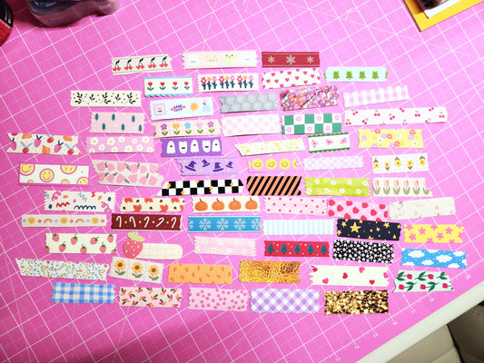 Collection of colorful washi tape strips on a pink cutting mat