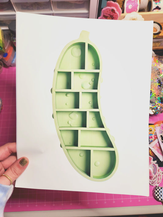 Green silicone ice cube tray on a white sheet of paper held by a hand.