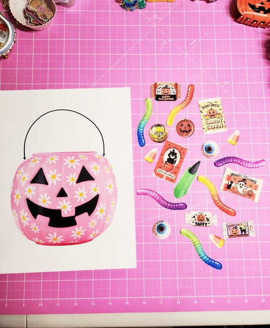 Pink Halloween candy bucket with accessories on a pink grid background
