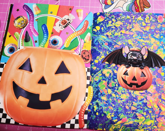 Halloween-themed items including a pumpkin with a bat on a colorful background.