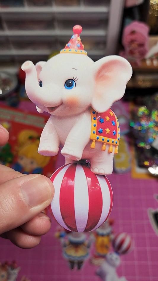 Toy elephant on a striped ball held by a hand with a colorful background