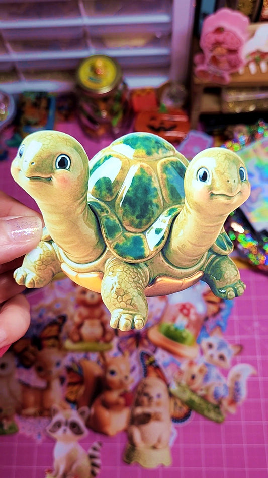 Two turtle figurines held against a colorful background with cartoon characters.