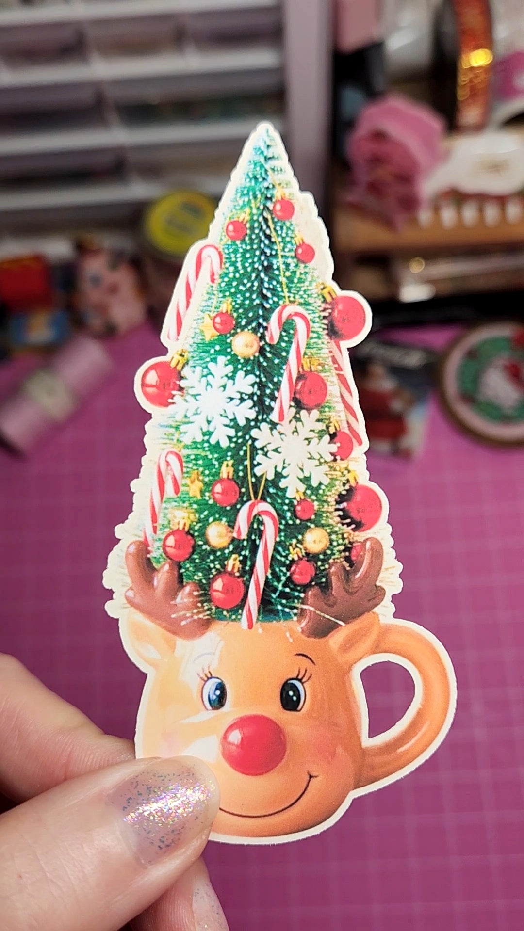 Decorative Christmas sticker with a reindeer face and candy cane tree design, held by a hand.