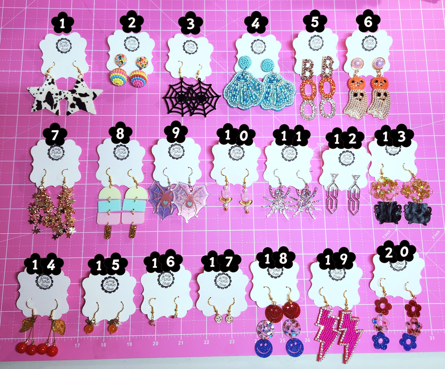 Assorted earrings on numbered cards against a pink grid background