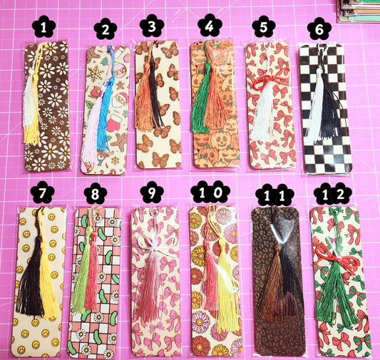 Set of twelve decorative bookmarks with tassels on a pink cutting mat.