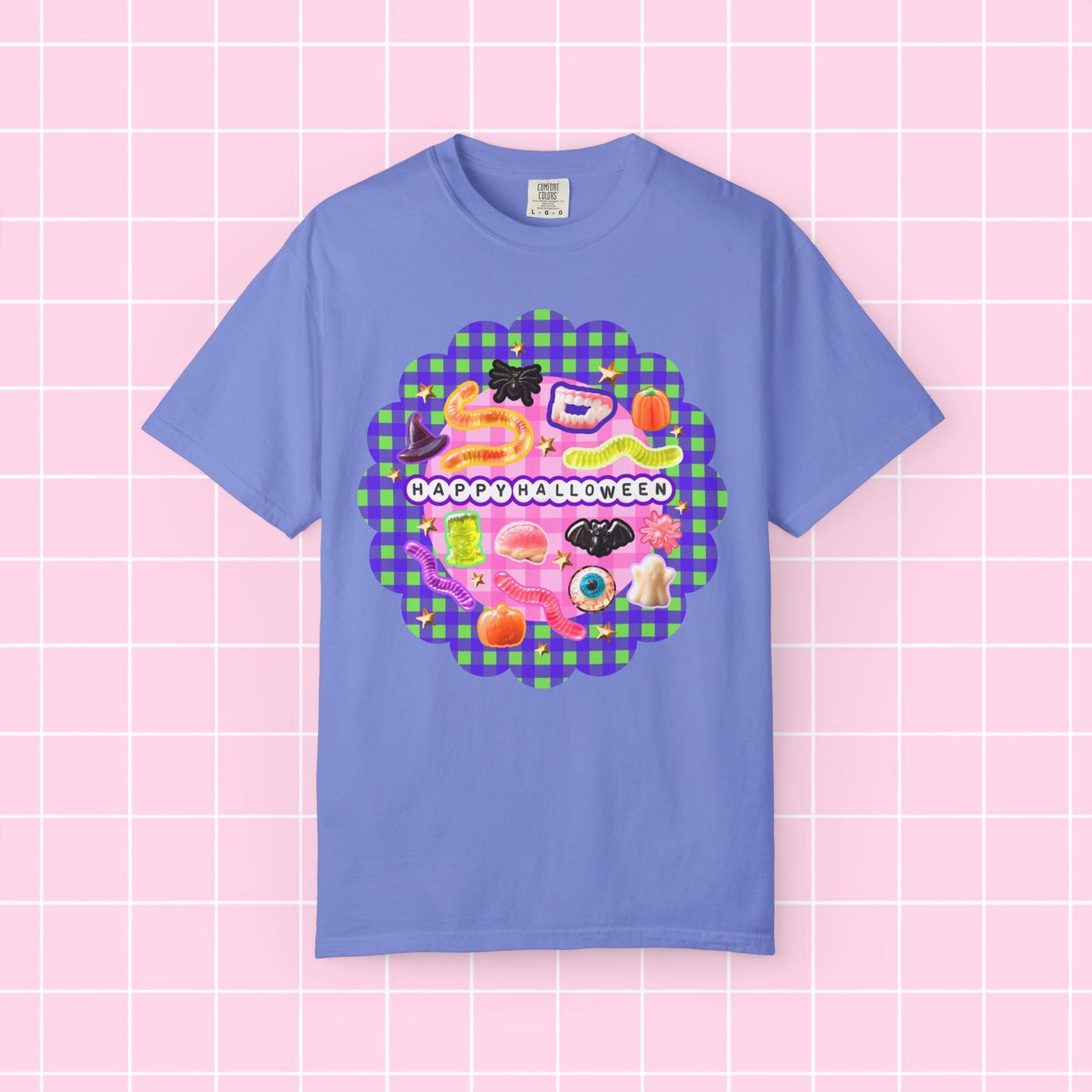 A light blue short-sleeve t-shirt with a colorful 'Happy Halloween' graphic on the chest, displayed against a pink grid background.