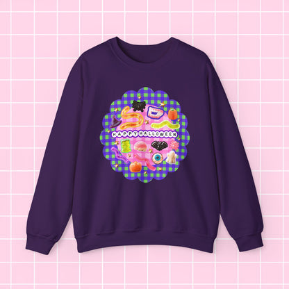 A dark purple crewneck sweatshirt featuring a colorful retro graphic on the chest with the text 'HAPPY BIRTHDAY' over a pink and green gingham patterned scalloped circle, displayed on a light pink grid background.