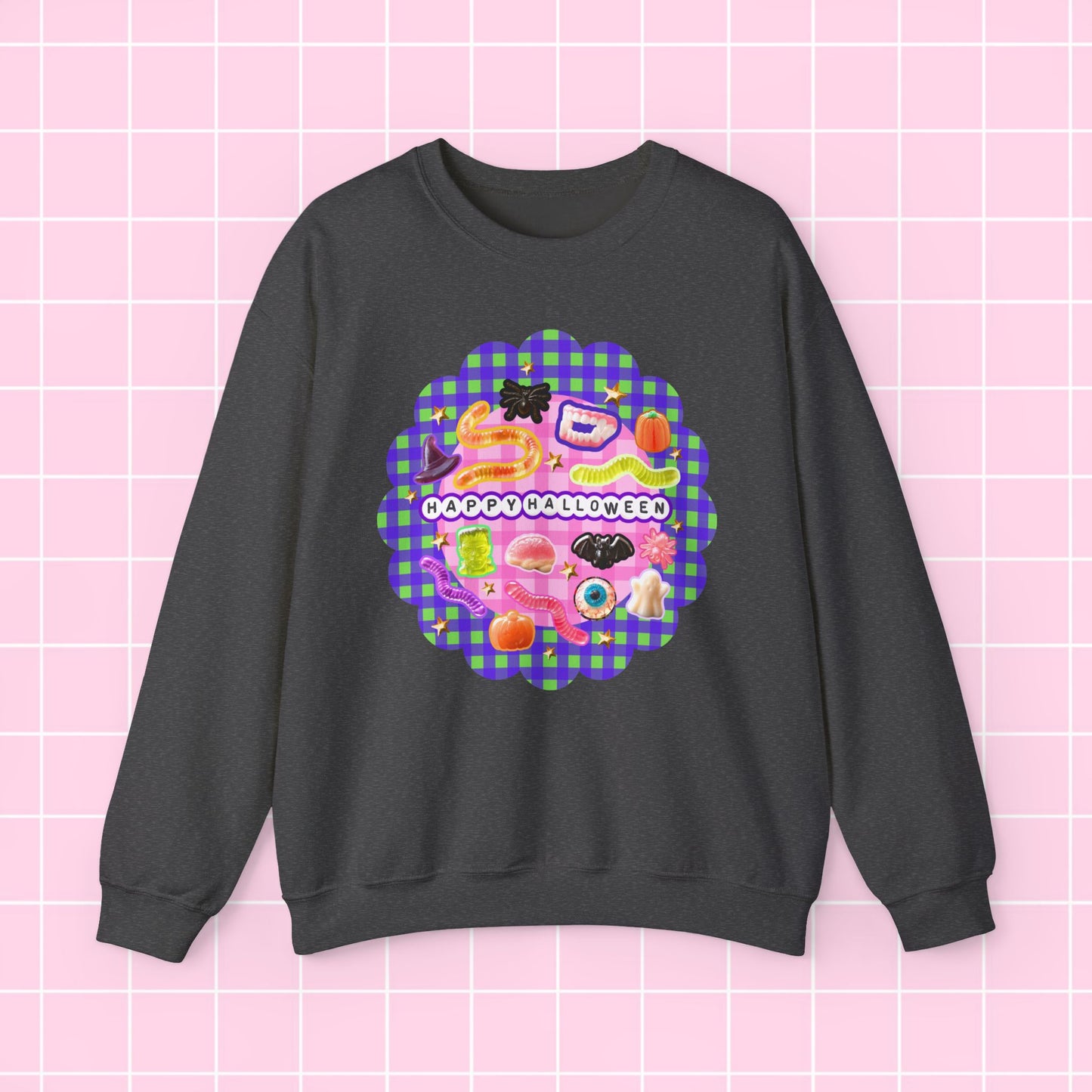A dark gray crewneck sweatshirt featuring a colorful retro-style graphic print on the front with the text 'I DON'T LIKE APPLES' over a pink and purple gingham pattern, displayed against a light pink grid background.