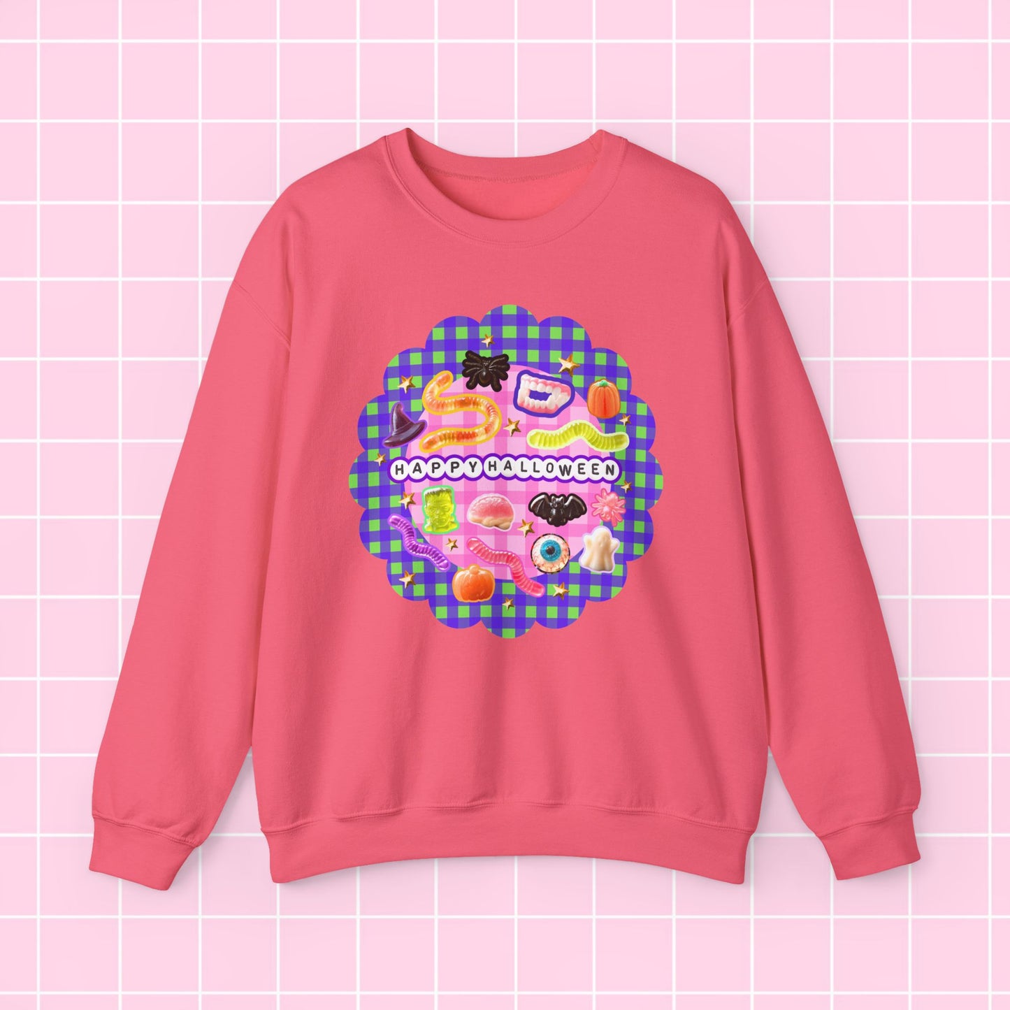 A pink crewneck sweatshirt featuring a colorful retro-style graphic print on the front with the text 'I DON'T LIKE APPLES' over a pink and green gingham pattern, displayed against a light pink grid background.