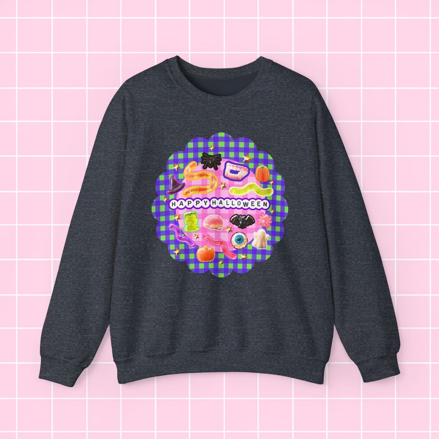 A dark heather gray crewneck sweatshirt featuring a colorful retro-style graphic on the chest with the text 'HAPPY OCCASIONALLY' over a pink and purple gingham pattern, displayed against a light pink grid background.