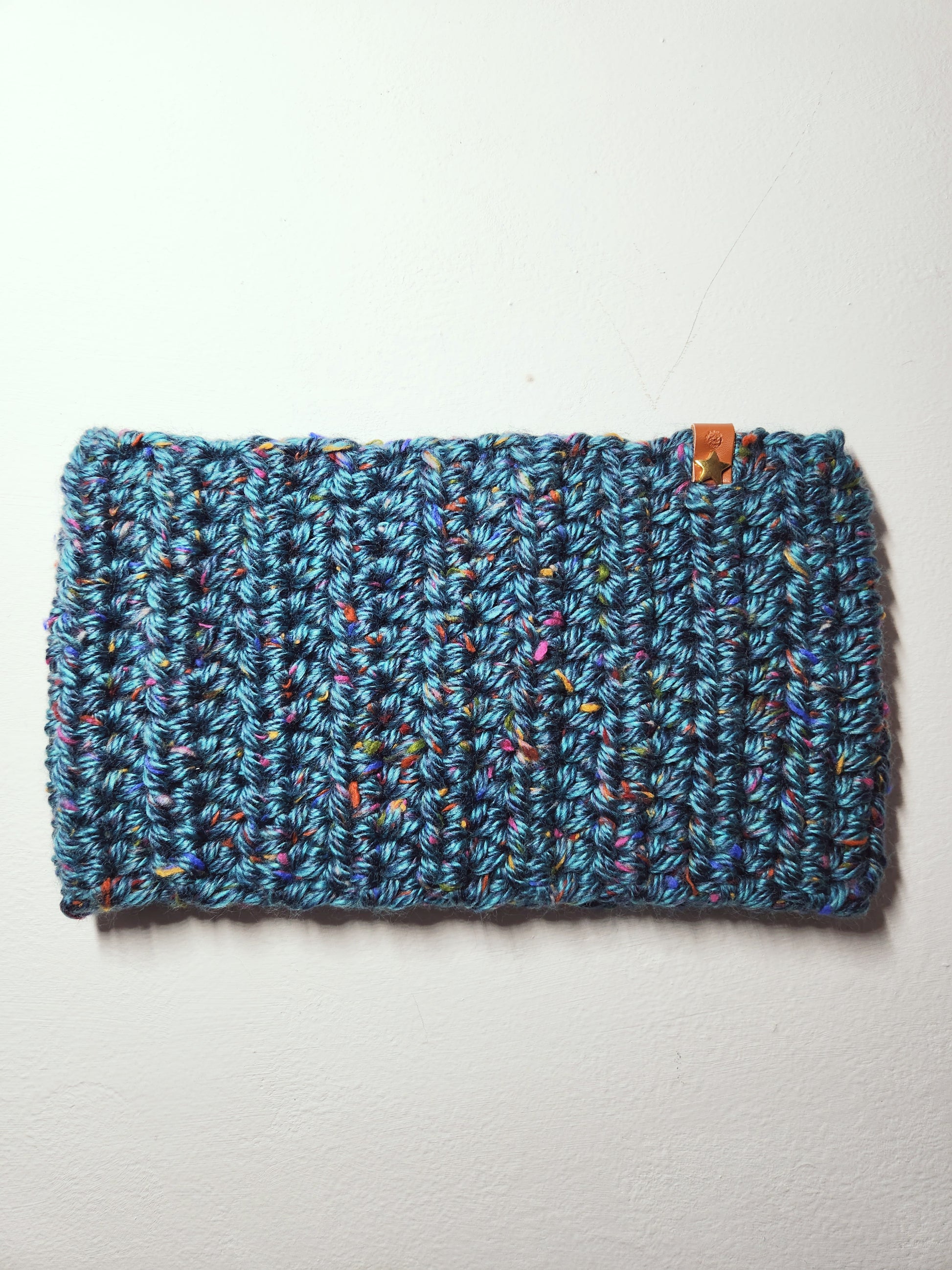 Blue knitted headband with multicolor speckles on a light gray background