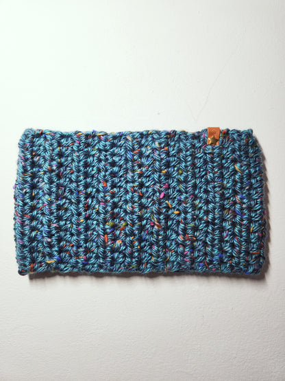 Blue knitted headband with multicolor speckles on a light gray background