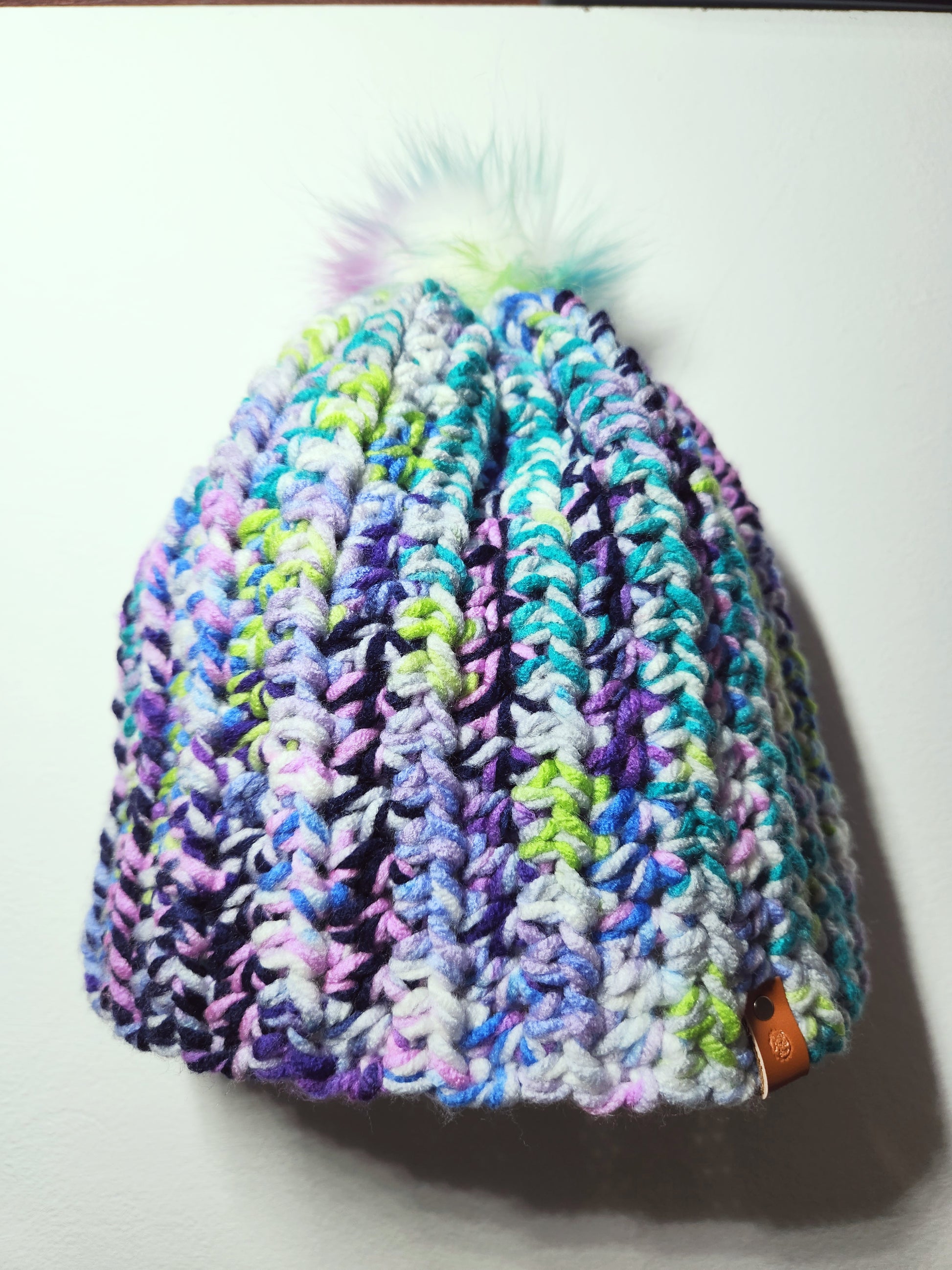 Multicolored knit beanie with a brand tag on a white background