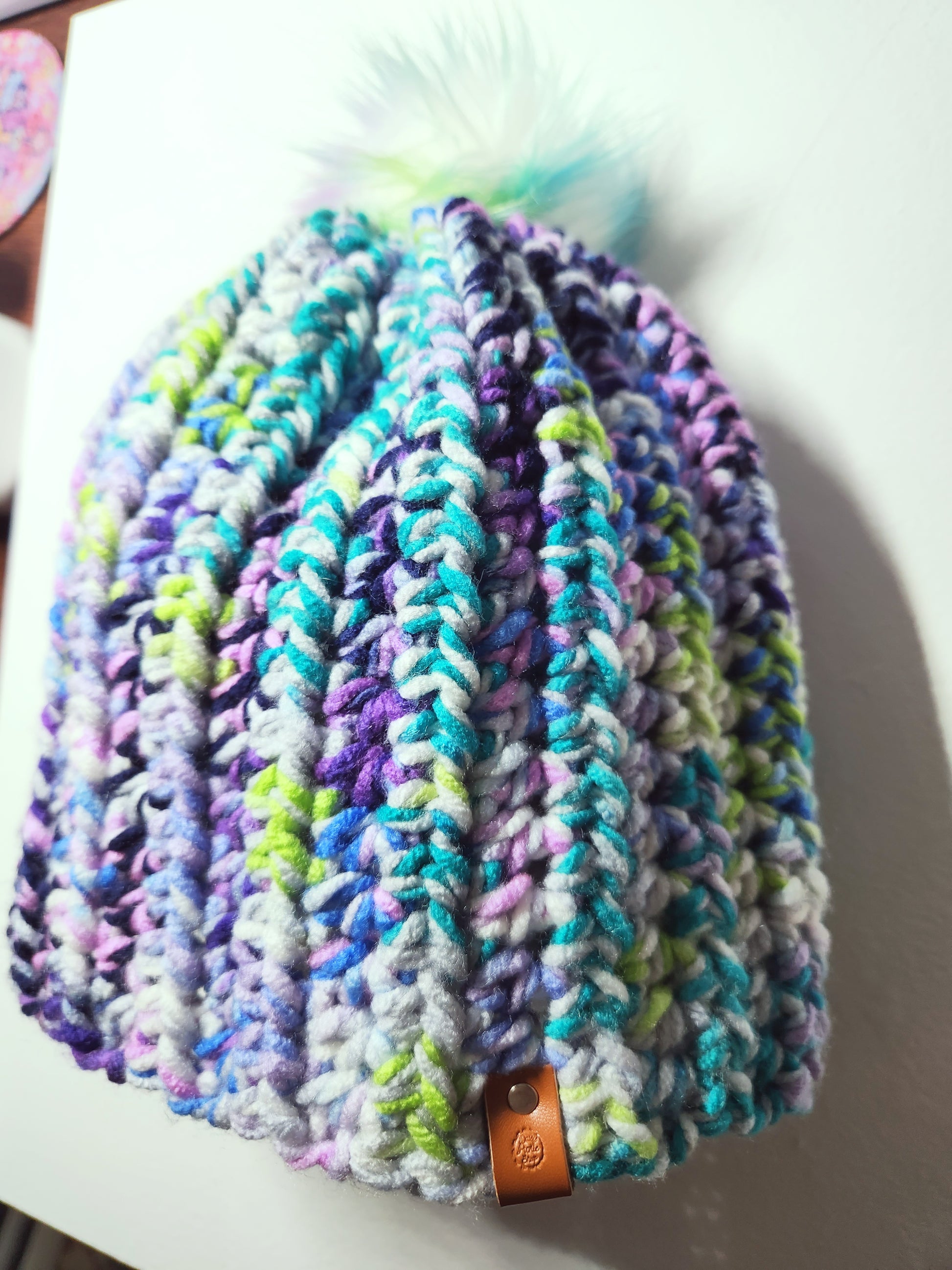 Colorful knitted beanie with a pom-pom on a white surface