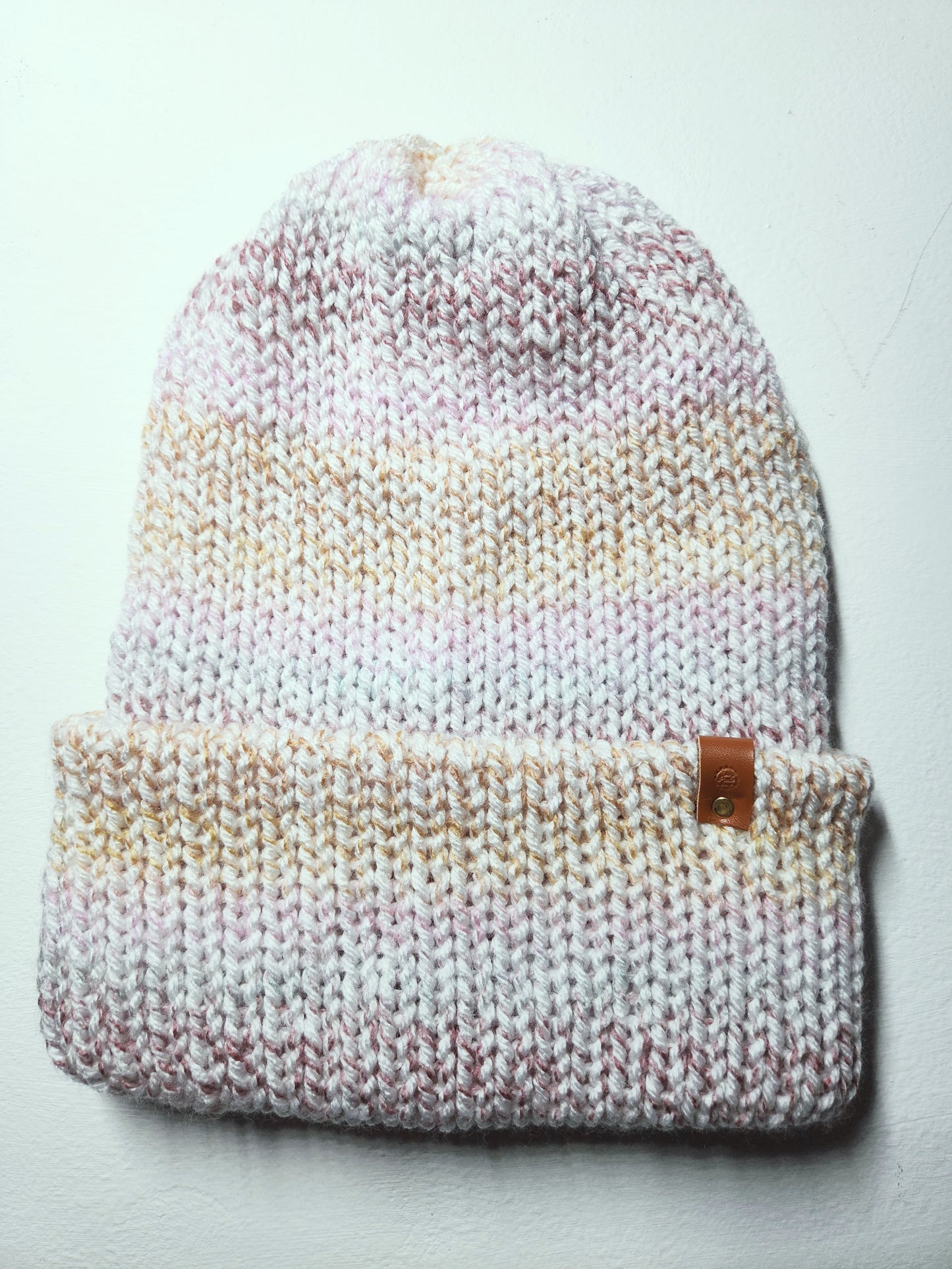 Knitted beanie with gradient color pattern on a light gray background