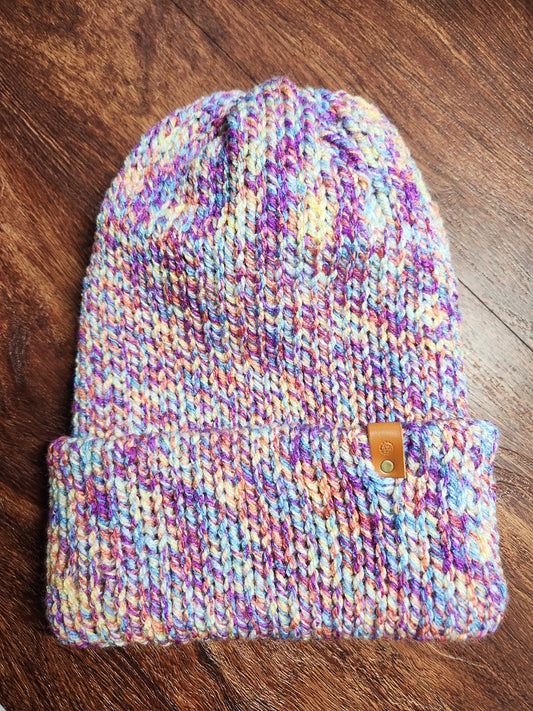 Multicolored knit beanie with a brand tag on a wooden surface