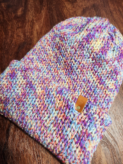 Multicolored knitted pouch with a leather patch on a wooden surface