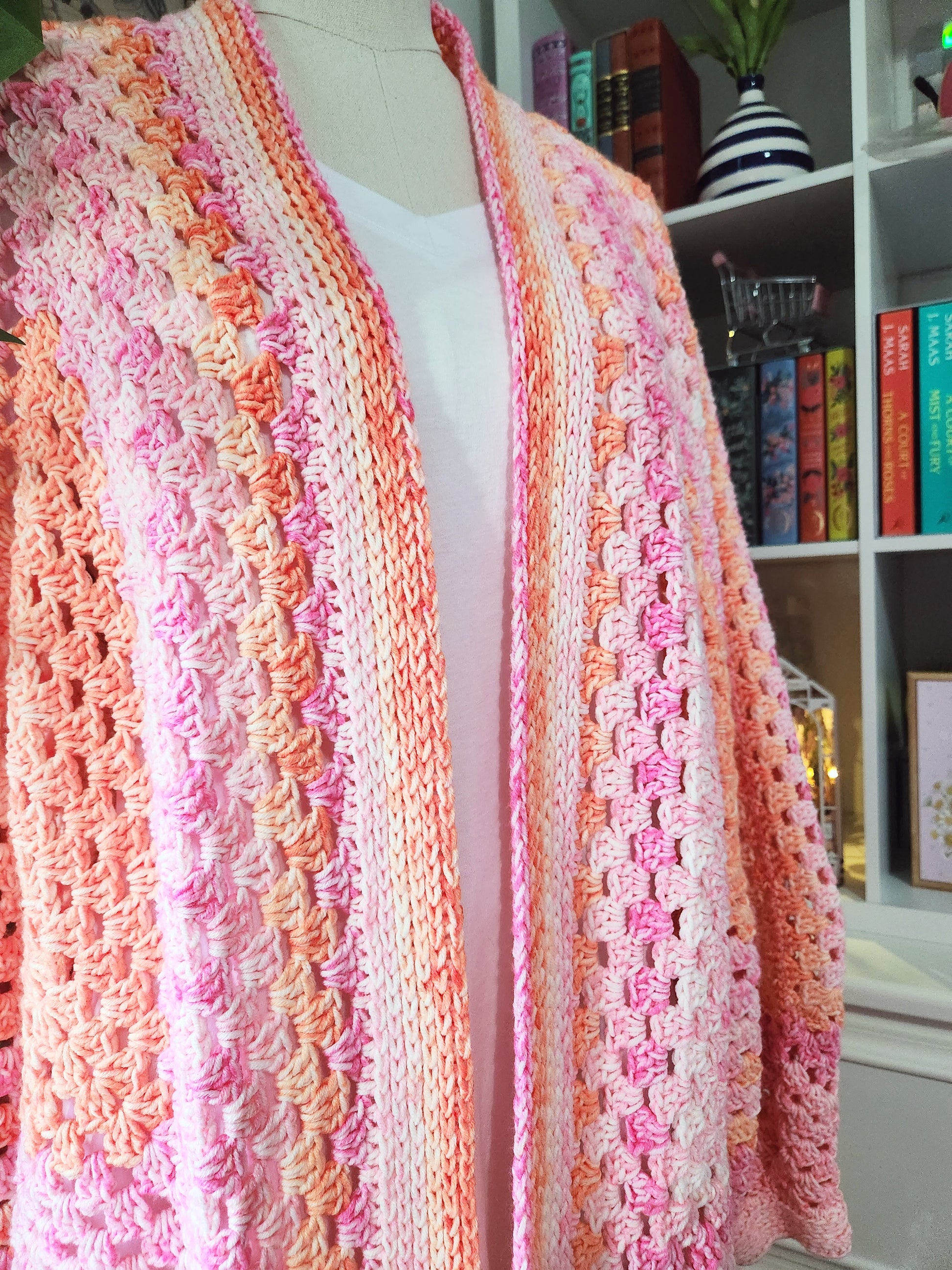 Colorful knitted cardigan on a mannequin against a bookshelf background