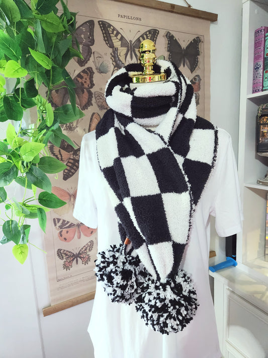 Person wearing a black and white checkered scarf with floral ends, standing in a room with butterfly decorations on the wall.