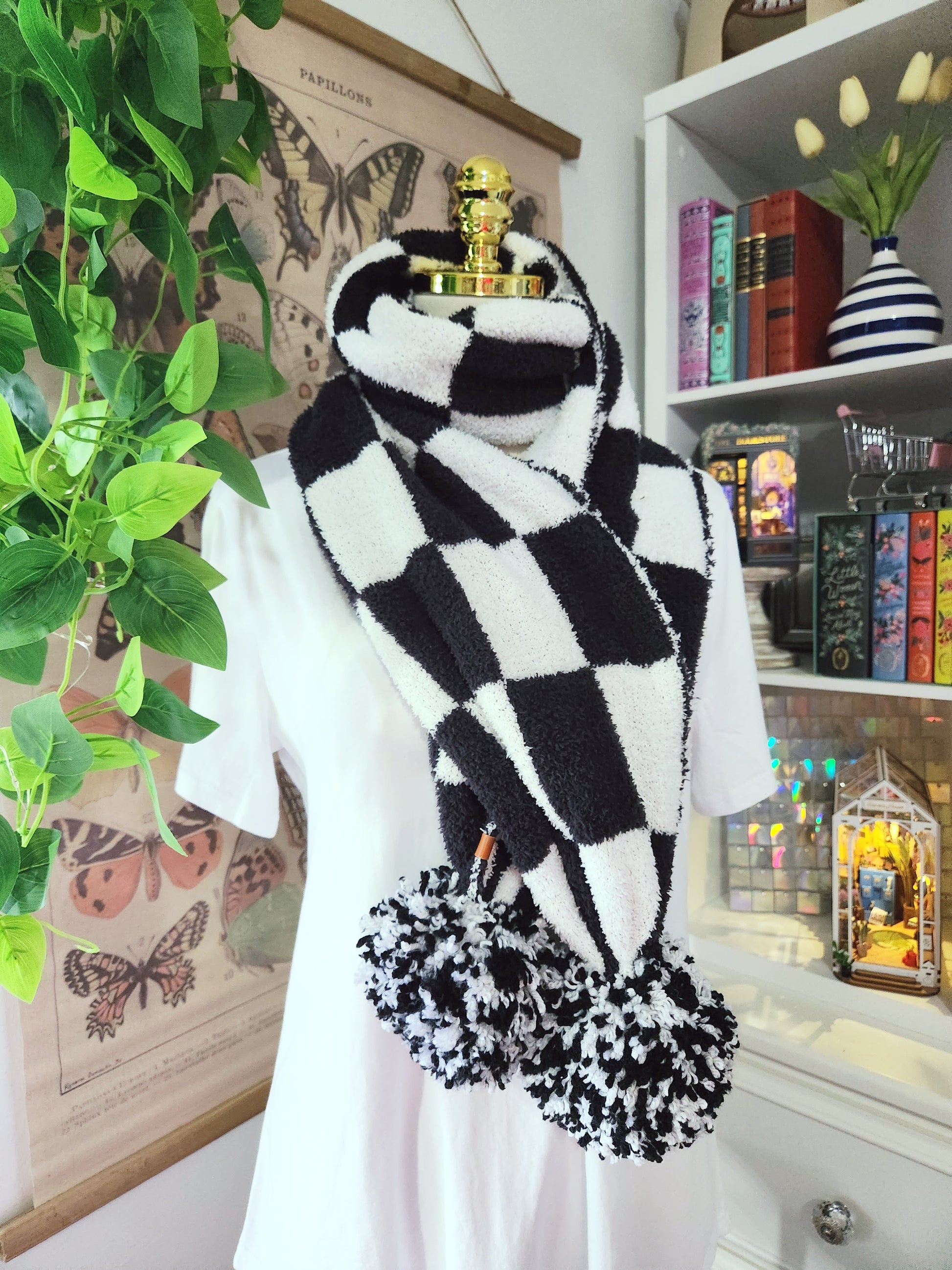 Black and white checkered scarf with pom-poms in a room setting