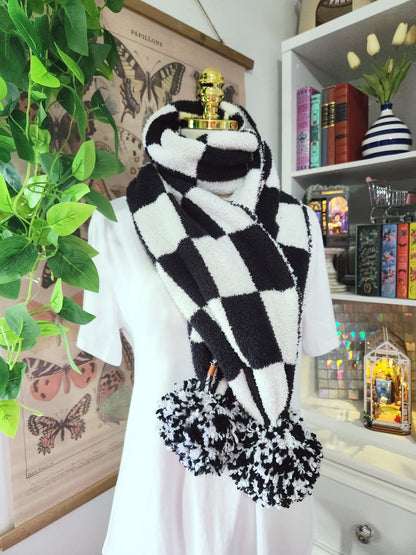 Black and white checkered scarf with pom-poms in a room setting