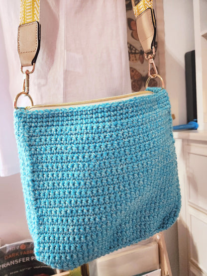 Blue woven handbag with beige strap on a white background