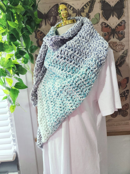 Knitted shawl draped over a mannequin against a butterfly-themed wall.