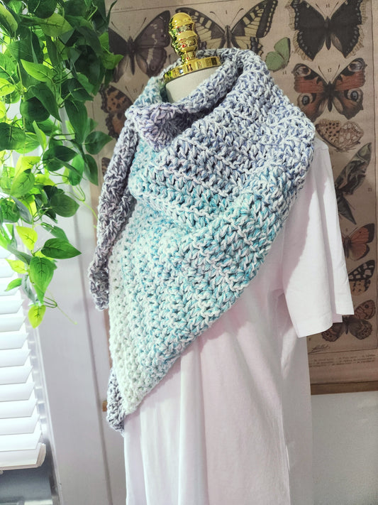 Knitted shawl draped over a mannequin against a butterfly-themed wall.