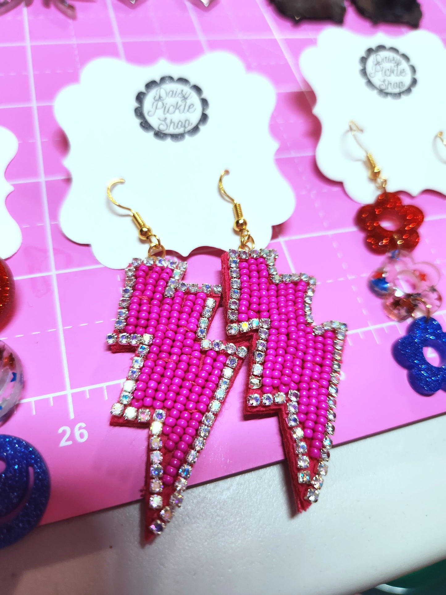Pink lightning bolt earrings on a pink background with 'Jewelry Pickle Shop' branding.