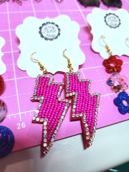 Pink lightning bolt earrings on a pink background with 'Jewelry Pickle Shop' branding.
