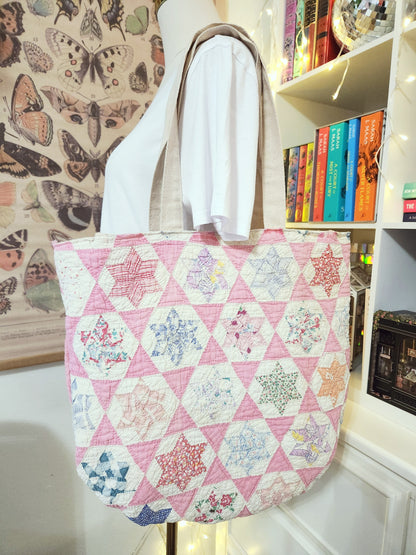 Quilted tote bag with floral hexagon pattern on a mannequin against a bookshelf background.