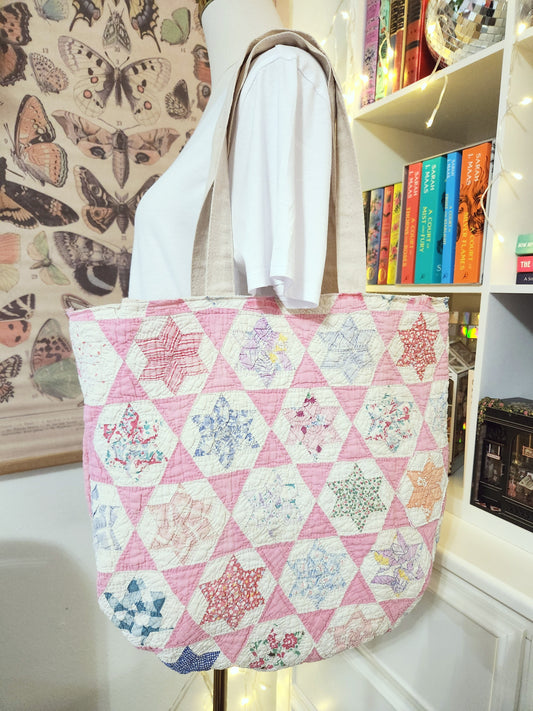 Quilted tote bag with floral hexagon pattern on a mannequin against a bookshelf background.