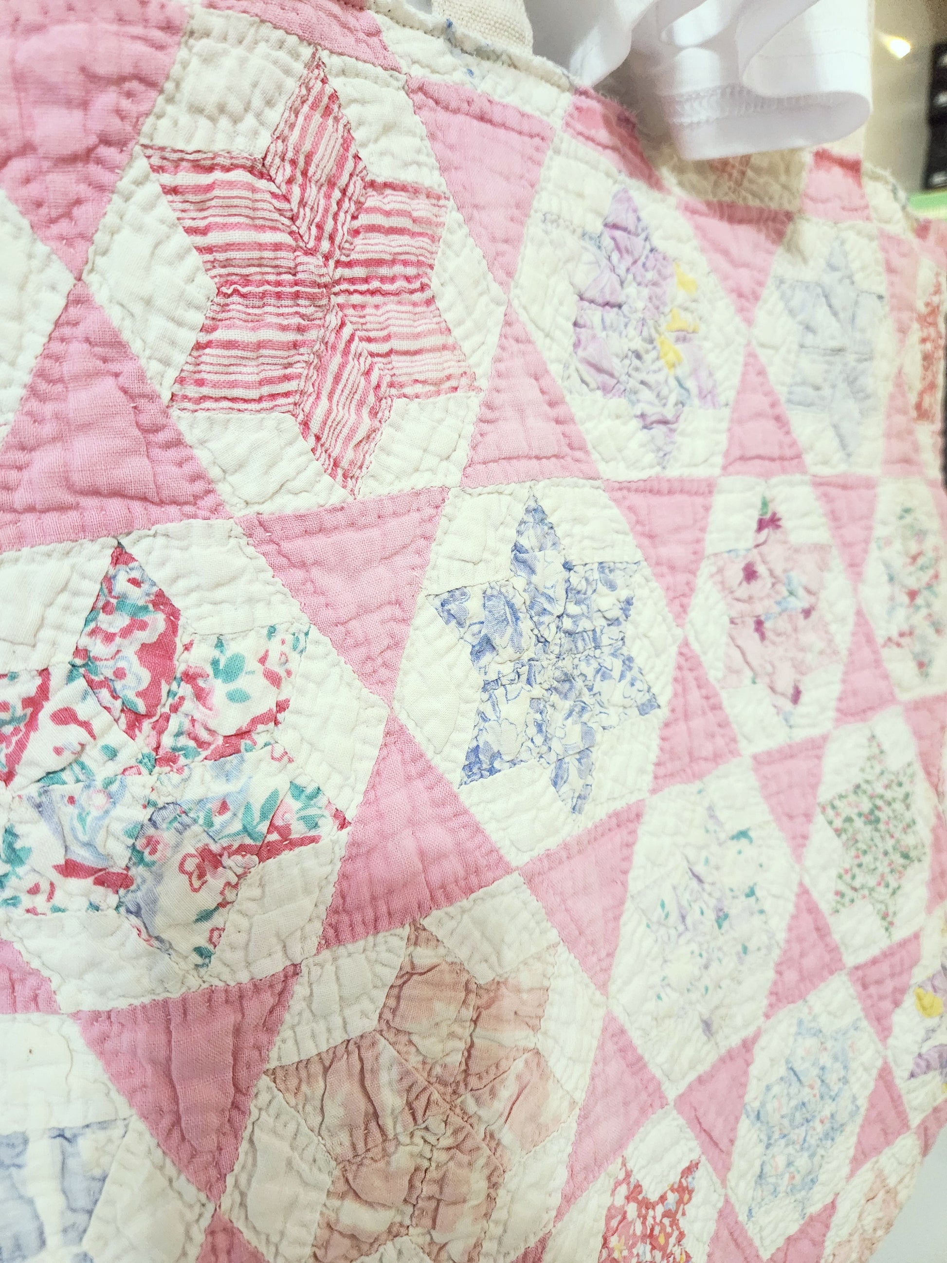 Quilt with pink and white hexagonal pattern, featuring floral designs.