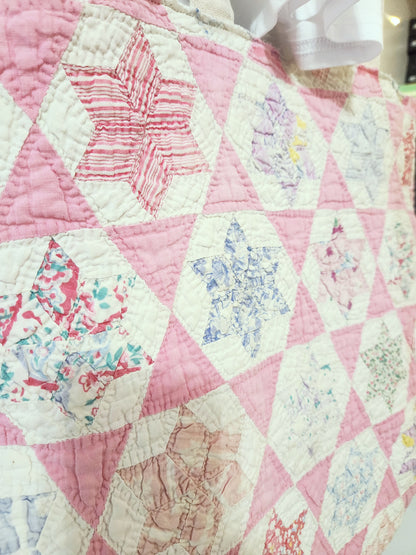 Quilt with pink and white hexagonal pattern, featuring floral designs.