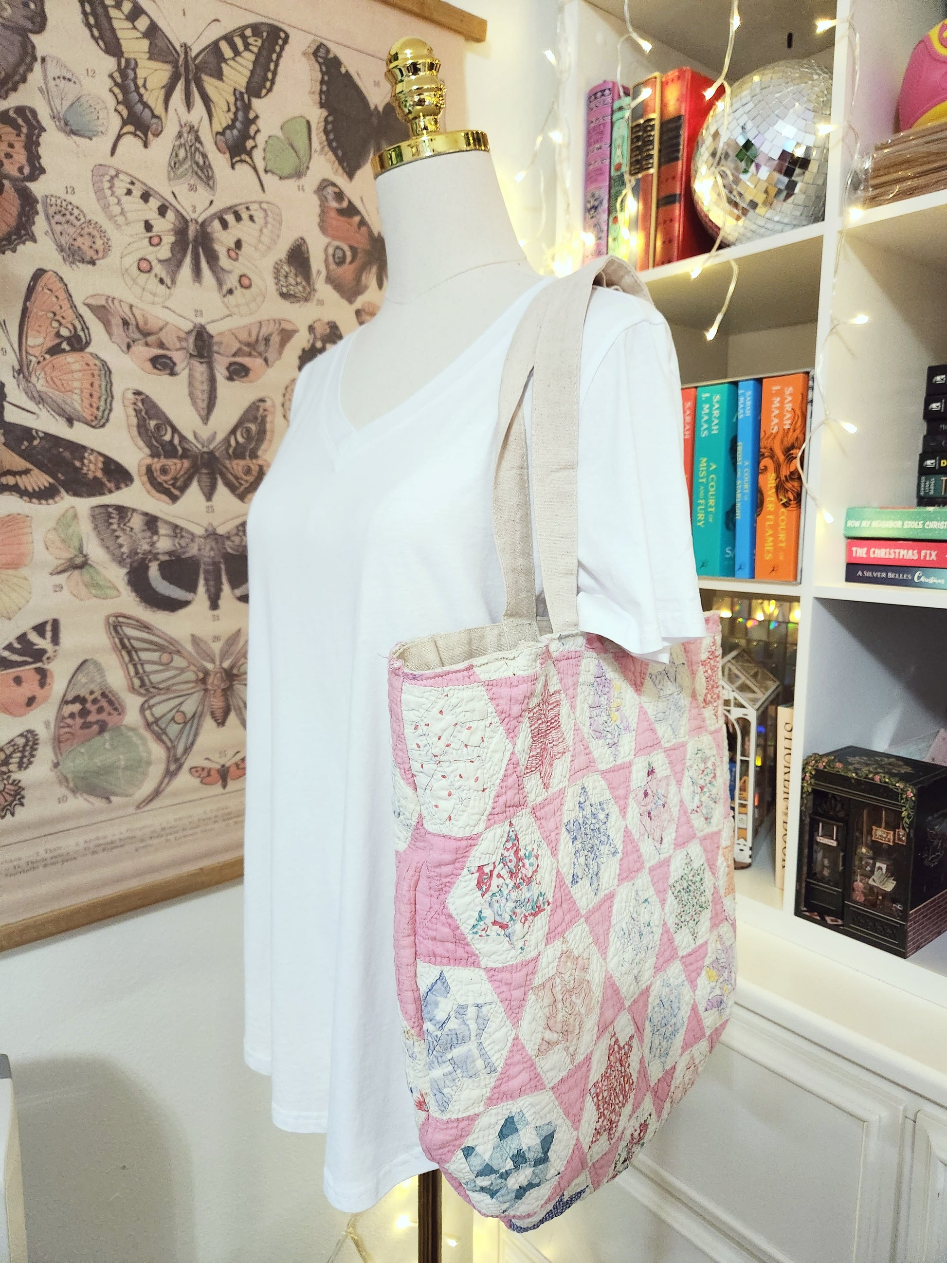 Mannequin wearing a white top with a pink floral bag in a room with butterfly wallpaper and books.