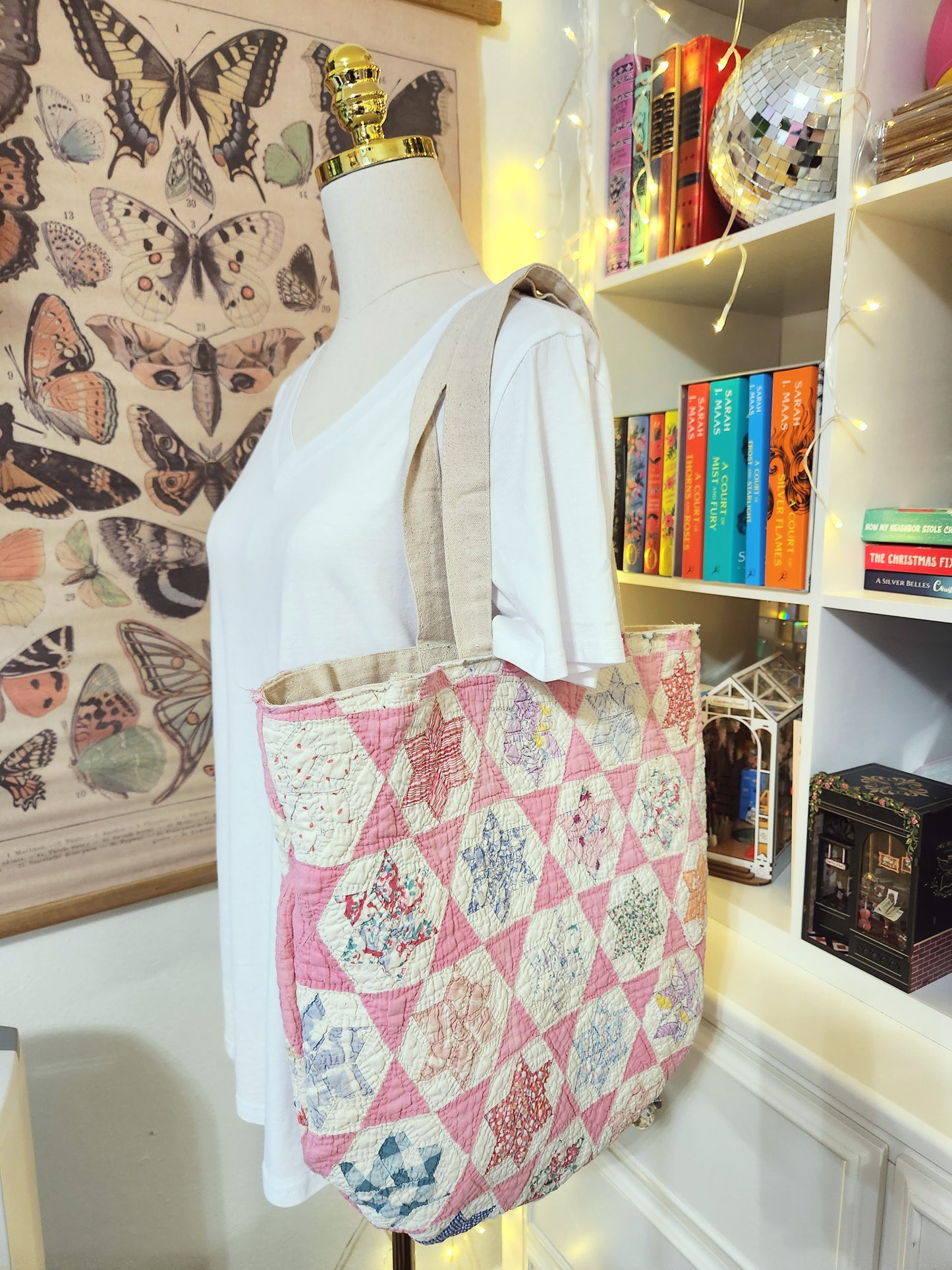 Mannequin wearing a white shirt with a pink quilted bag, butterfly wallpaper, and bookshelf in the background.